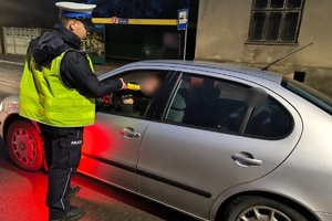 Zdjęcie przedstawia policjanta kontrolującego trzeźwość kierowcy.