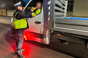 Zdjęcie przedstawia policjanta kontrolującego trzeźwość kierowcy.