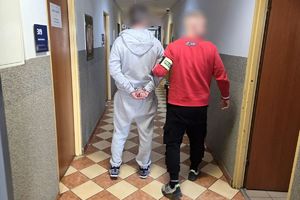 Zdjęcie przedstawia policjanta prowadzącego zatrzymanego.