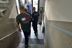Zdjęcie przedstawia policjantów prowadzących zatrzymanego.