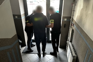 Zdjęcie przedstawia policjantów prowadzących zatrzymanego.