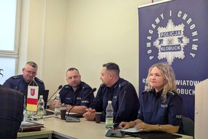 Zdjęcie przedstawia policjantów siedzących przy biurku.