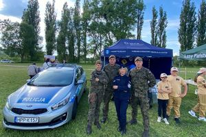 Zdjęcie przedstawia policjantkę, żołnierzy oraz radiowóz.