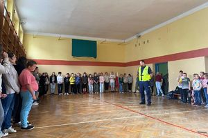 Zdjęcie przedstawia policjanta oraz dzieci w sali.