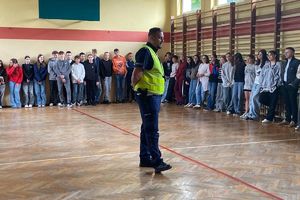 Zdjęcie przedstawia policjanta oraz dzieci w sali.