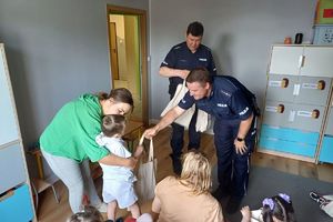 Zdjęcie przedstawia policjantów wręczających prezenty dzieciom.