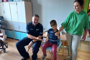 Zdjęcie przedstawia policjanta, chłopca oraz nauczycielkę.