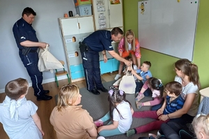 Zdjęcie przedstawia policjantów wręczających prezenty dzieciom.