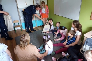 Zdjęcie przedstawia policjantów wręczających prezenty dzieciom.