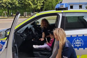dzieci siedzą w radiowozie z policjantką