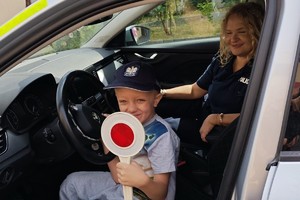 dzieci siedzą w radiowozie z policjantką