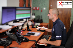 Zdjęcie przedstawia policjanta przy biurku z monitorami.