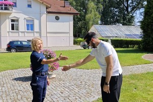 Zdjęcie przedstawia policjantkę oraz chłopaka w goglach, który próbuje podać dłoń policjantce.