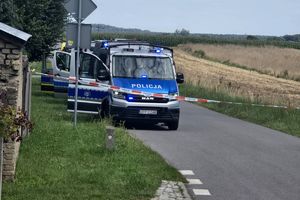 Zdjęcie przedstawia policyjne radiowozy ustawione przy drodze.