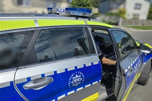 Zdjęcie przedstawia radiowóz wewnątrz, którego siedzi zatrzymany.