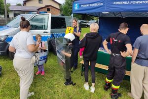 umundurowana policjantka i policjant na pikniku prezentują dzieciom sprzęt policyjny