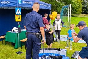 umundurowana policjantka i policjant na pikniku prezentują dzieciom sprzęt policyjny