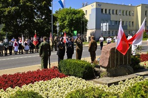 uczestnicy obchodów maszerują oraz składają wiązanki kwiatów pod miejscami pamięci narodowej