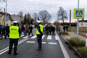 umundurowani policjanci zabezpieczają kolumnę pieszych przechodzącą przez pasy