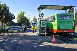 autobus jest sprawdzany technicznie na mobilnej stacji przez funkcjonariusza obok stoją radiowozy i umundurowani policjanci