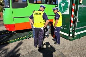autobus jest sprawdzany technicznie na mobilnej stacji przez funkcjonariusza obok stoją umundurowani policjanci
