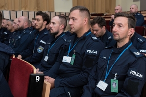 umundurowani policjanci siedzą w auli na krzesłach