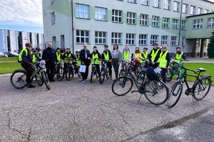 uczniowie w kamizelkach odblaskowych z rowerami  pozują do zdjęcia, obok stoi umundurowany policjant