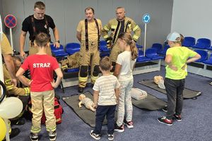 na zdjęciu policjanci oraz uczestnicy festynu, dzieci w kamizelkach odblaskowych, policjanci w mundurach oraz strażacy ochotnicy