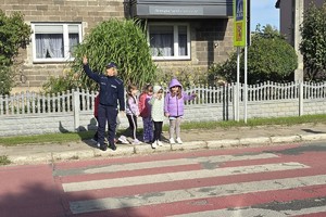 policjanci i policjantki pokazują dzieciom jak w praktyce poprawnie przechodzić przez przejście dla pieszych