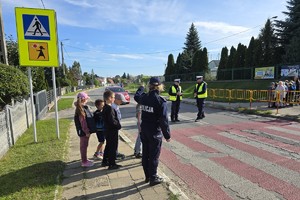 policjanci i policjantki pokazują dzieciom jak w praktyce poprawnie przechodzić przez przejście dla pieszych