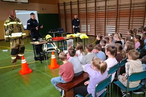 umundurowani policjanci stoją przed dziećmi, prowadzą prelekcje, pokazują odblaski