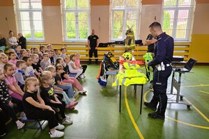 umundurowany policjant okazuje dzieciom odblaski