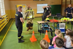 strażacy stoją przed dziećmi, prowadzą prelekcje, pokazują odblaski