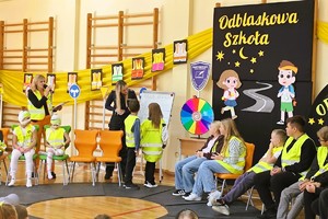 na zdjęciu umundurowane policjant i dzieci w odblaskowych kamizelkach, działania na sali sportowej