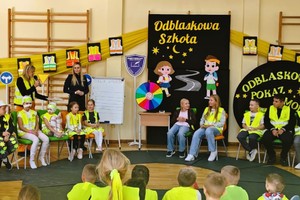 na zdjęciu umundurowane policjant i dzieci w odblaskowych kamizelkach, działania na sali sportowej