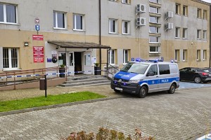Na zdjęciu budynek Starostwa Powiatowego w Kłobucku, przed którym zaparkowany jest radiowóz policyjny. W tle widać wejście do urzędu i tablicę informacyjną.