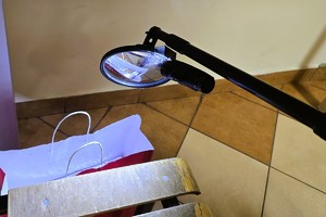 Na zdjęciu stół z lampą i torbą policyjną znajdujący się w pomieszczeniu urzędu.