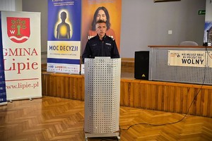 Policjant w mundurze przemawia przy mównicy.