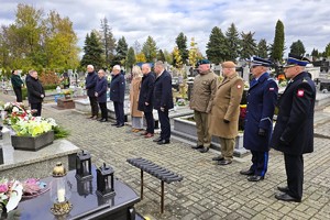 Przedstawiciele służb i władz samorządowych stojący w zadumie przy miejscu pamięci.