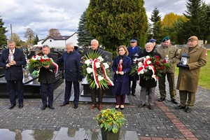 Delegacja z wiązankami kwiatów podczas uroczystości na cmentarzu.