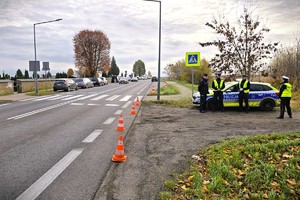 umundurowani policjanci stoją przy radiowozie w rejonie cmentarza