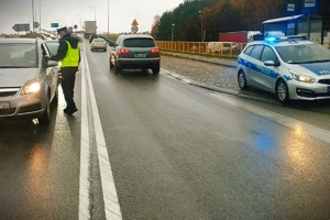 umundurowany policjant kontroluje stan trzeźwości kierowcy srebrnego opla