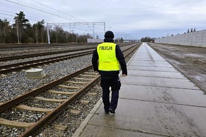 umundurowany policjant idzie przy torowisku