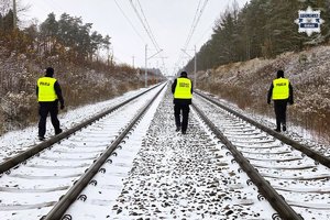 funkcjonariusze w mundurach idą wzdłuż torowiska