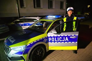 umundurowany policjant stoi przed radiowozem