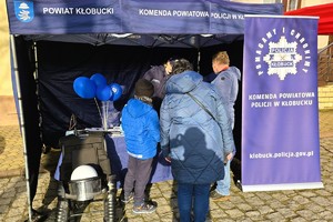 Policjantki z Komendy Powiatowej Policji w Kłobucku prowadzą rozmowy informacyjne z uczestnikami wydarzenia przy policyjnym stoisku.