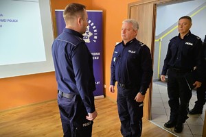 Odprawa służbowa policjantów, na zdjęciu widać grupę umundurowanych policjantów oraz kobiety i mężczyzn ubranych po cywilnemu, w tle rzutnik, na którym prezentowane są treści dotyczące bezpieczeństwa powiatu kłobuckiego
