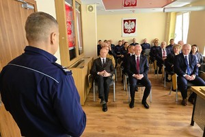 Odprawa służbowa policjantów, na zdjęciu widać grupę umundurowanych policjantów oraz kobiety i mężczyzn ubranych po cywilnemu, w tle rzutnik, na którym prezentowane są treści dotyczące bezpieczeństwa powiatu kłobuckiego