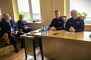 Odprawa służbowa policjantów, na zdjęciu widać grupę umundurowanych policjantów oraz kobiety i mężczyzn ubranych po cywilnemu, w tle rzutnik, na którym prezentowane są treści dotyczące bezpieczeństwa powiatu kłobuckiego