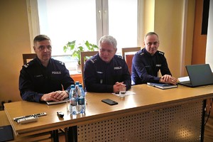 Odprawa służbowa policjantów, na zdjęciu widać grupę umundurowanych policjantów oraz kobiety i mężczyzn ubranych po cywilnemu, w tle rzutnik, na którym prezentowane są treści dotyczące bezpieczeństwa powiatu kłobuckiego
